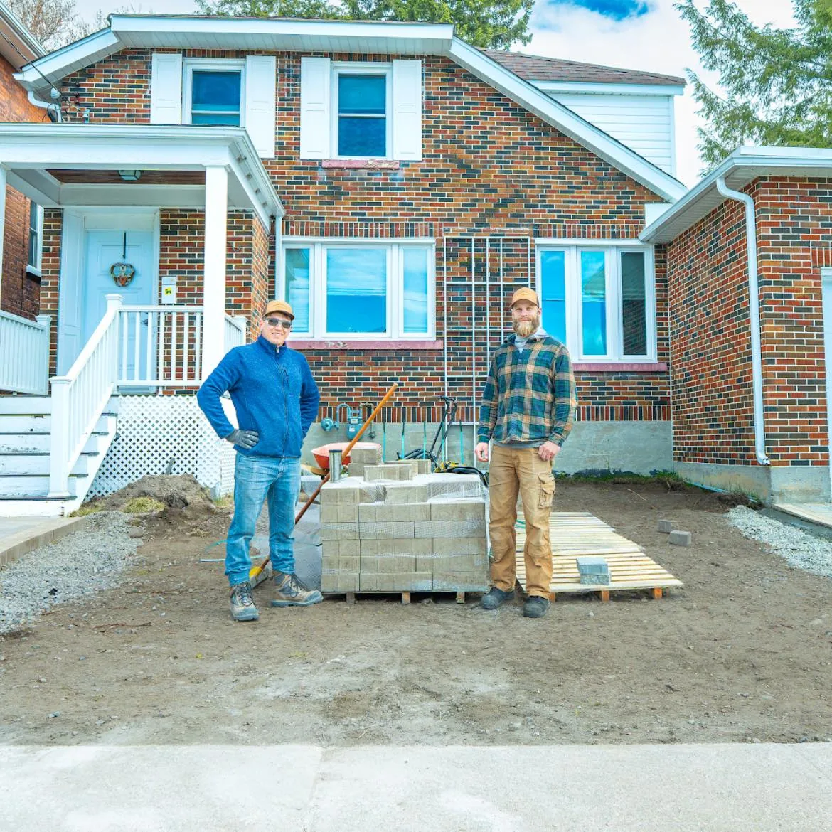 Bouwers Design Landscaping crew standing in front of a North Bay brick home with a pallet of interlock pavers, ready to start a hardscape install.