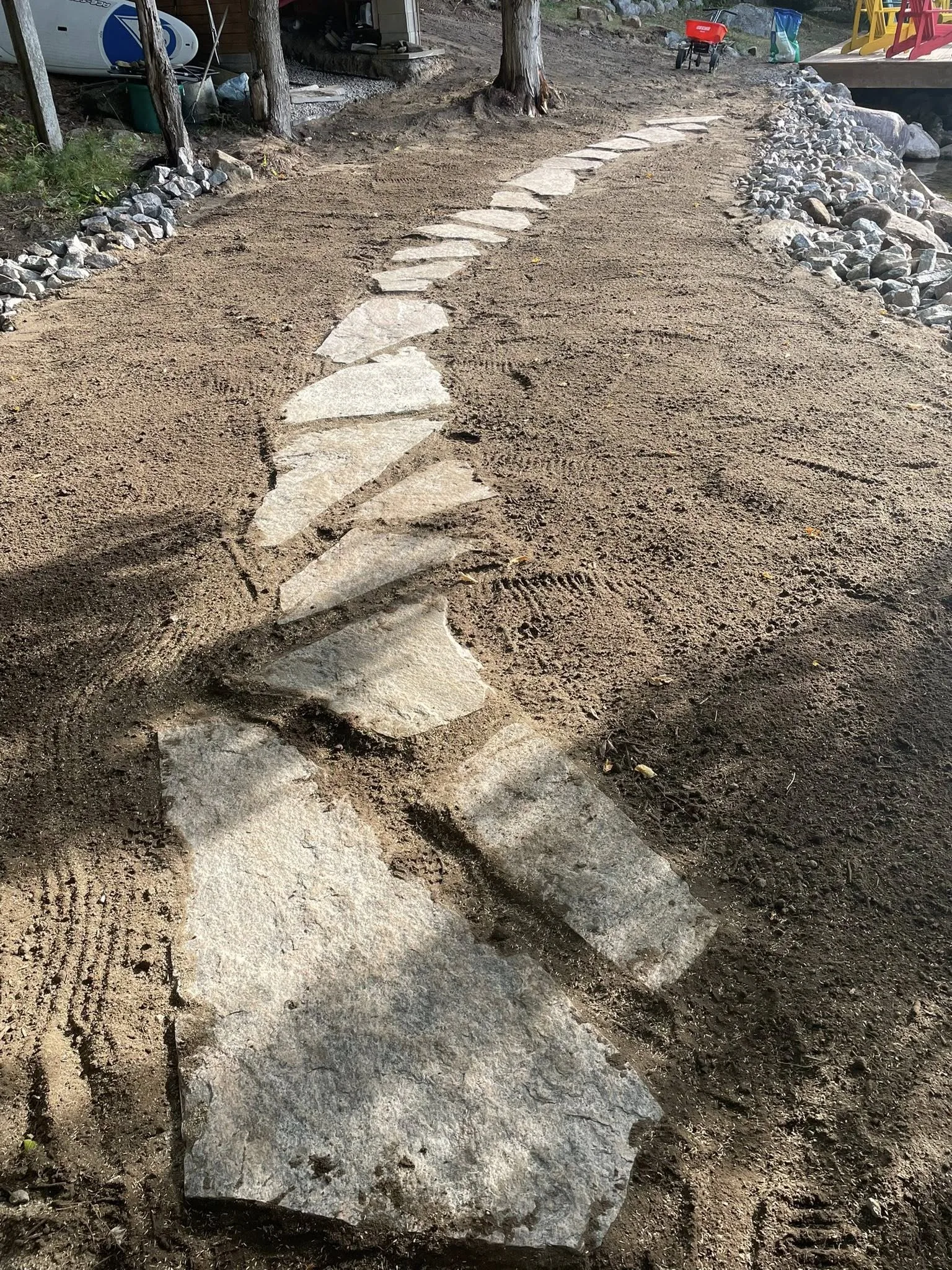Hand-fit irregular flagstone stepping-stone walkway laid by Bouwers Design Landscaping at a North Bay cottage property, with natural stone pieces set into compacted base.