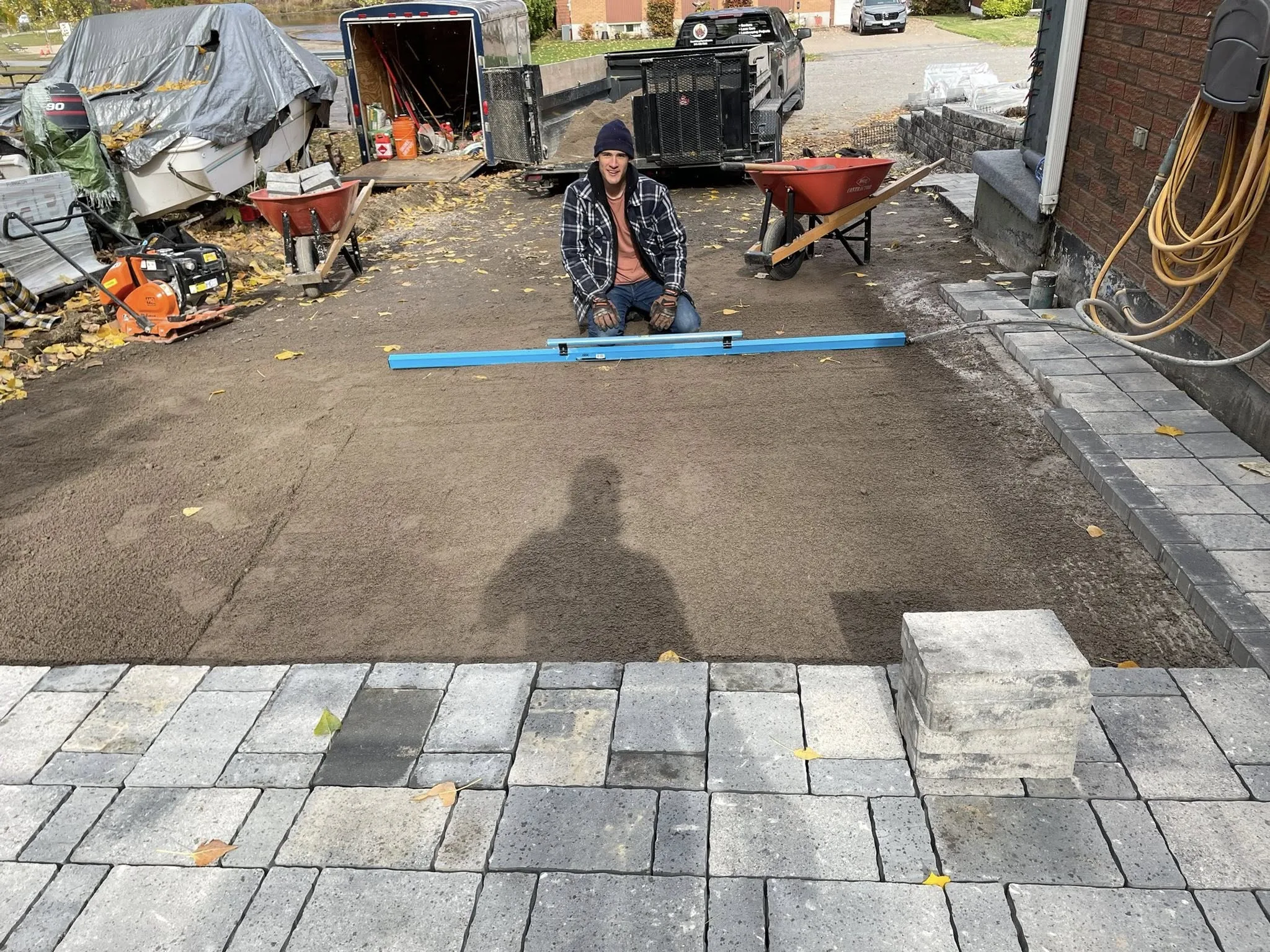 Bouwers Design Landscaping crew screeding compacted HPB aggregate base ahead of an interlock driveway install, the same base spec Bouwers runs on Powassan, Ontario residential and Hwy 11 corridor jobs.