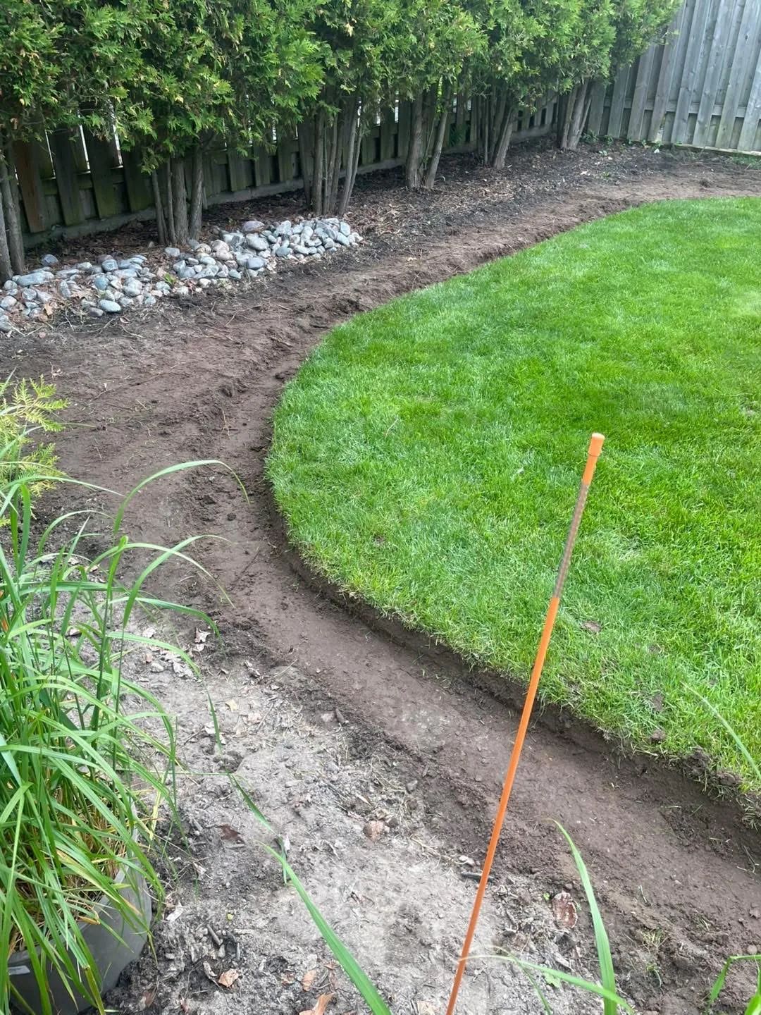 Curved sod transition meeting a fresh garden bed on a Bouwers landscape build in North Bay.